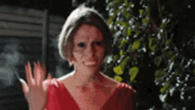 a woman in a red dress is waving her hand in the air .
