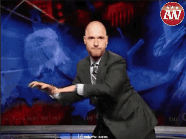 a man in a suit and tie is dancing in front of a wall that says an
