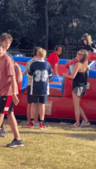 a boy wearing a jersey with the number 39 on it is standing in front of a bouncy house .