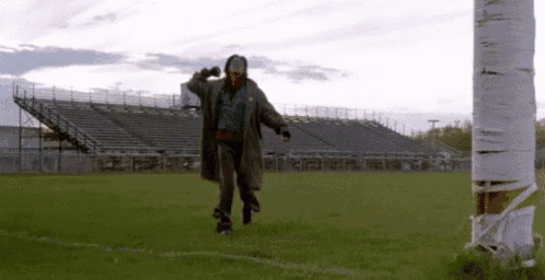 a man in a trench coat is rollerblading on a field .