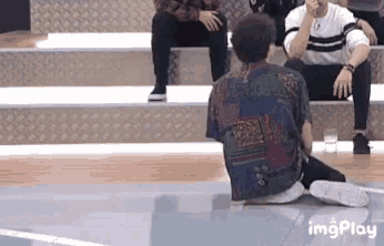 a man is sitting on the floor with a skateboard in his hand .