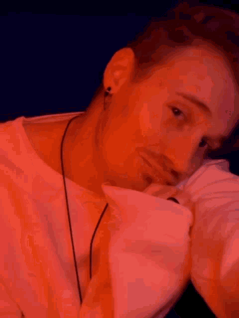 a close up of a man 's face with a pink shirt on