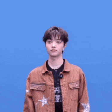 a young man wearing a brown jacket with stars on the sleeves is making a funny face