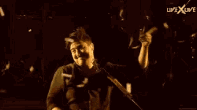 a man is standing in front of a microphone with his arms outstretched .
