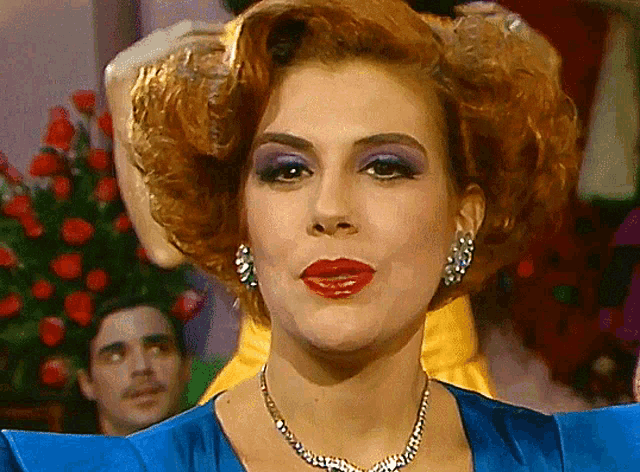 a woman wearing a blue dress and a necklace is making a funny face