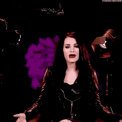 a woman in a leather jacket is standing in front of a microphone with the name paige written on it