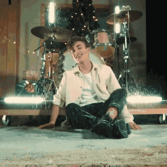 a man sitting on the floor in front of a drum set