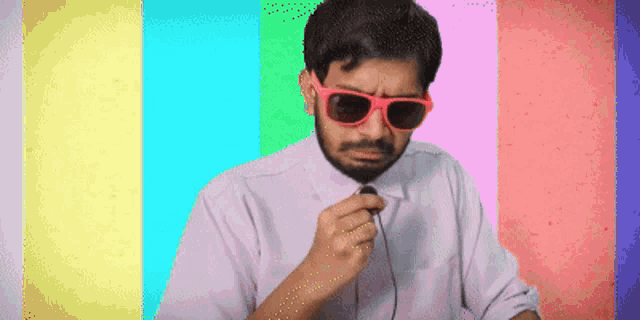 a man wearing sunglasses and a tie holds a microphone