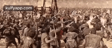 a large group of people are fighting each other in a battle in a field .