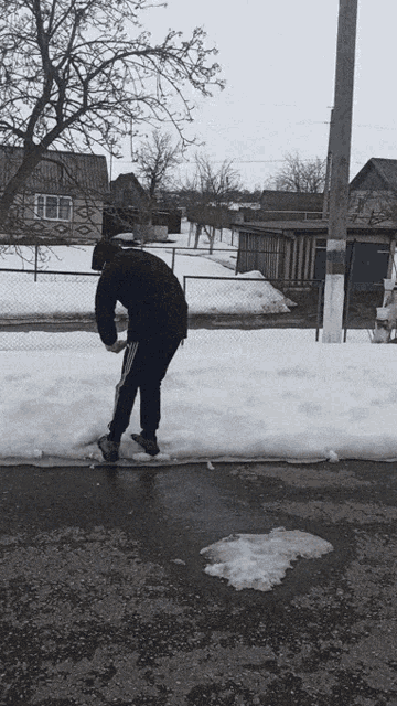 a person standing on a snowy sidewalk with a house in the background