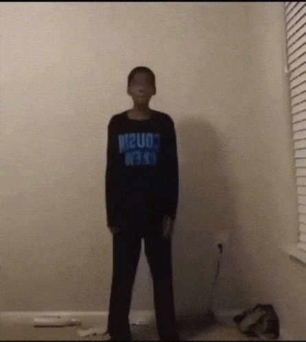 a boy is standing in a room wearing a shirt that says m2uo3 on it