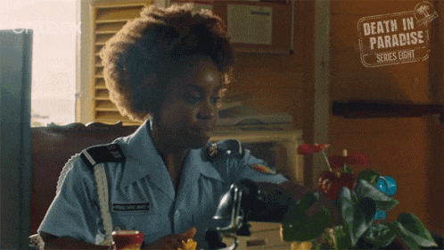 a woman in a police uniform is giving the peace sign .