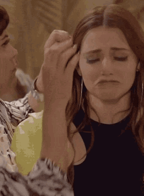 a woman is getting her hair done by another woman who is making a sad face
