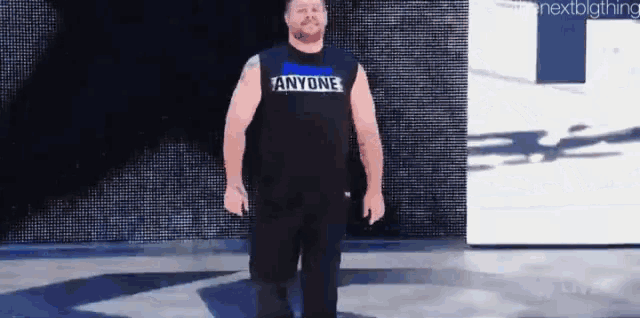 a man wearing a black tank top that says anyone