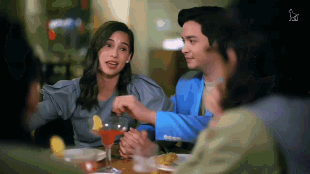 a group of people are sitting at a table with a martini in front of them