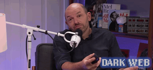 a man is sitting in front of a microphone with the words dark web behind him