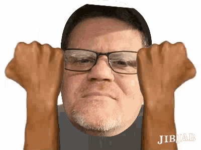 a man with glasses and a beard is making a funny face with his fists in the air .
