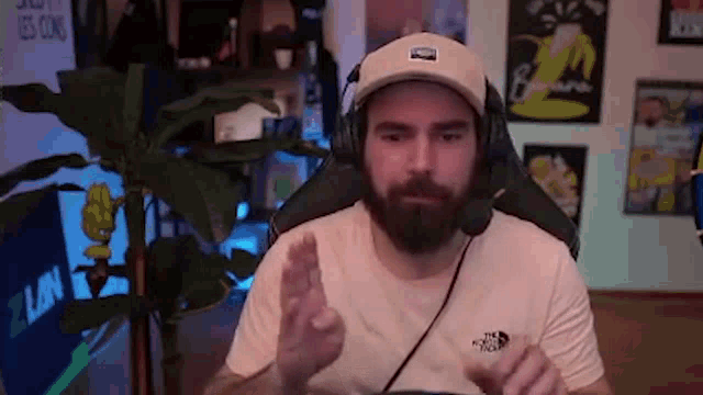 a man with a beard wearing headphones and a hat is sitting in a chair .