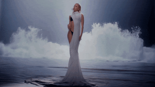 a woman in a long white dress is standing in the water