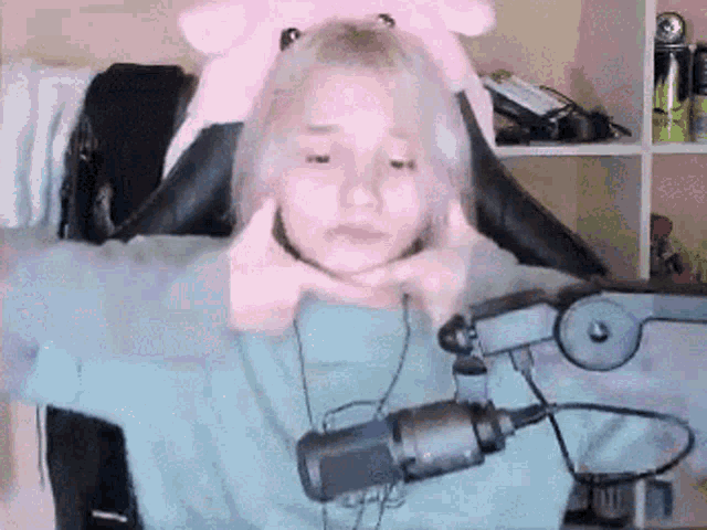 a girl is sitting in front of a microphone wearing headphones and a pink hat .