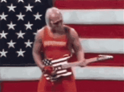 a man is standing in front of an american flag playing a guitar .
