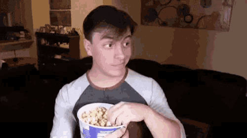 a young man is eating popcorn in a living room .