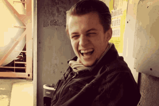 a young man is laughing in front of a sign that says " warning "