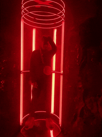 a man is standing in a red lighted cylinder