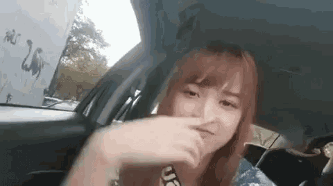 a woman is sitting in the back seat of a car and making a funny face .