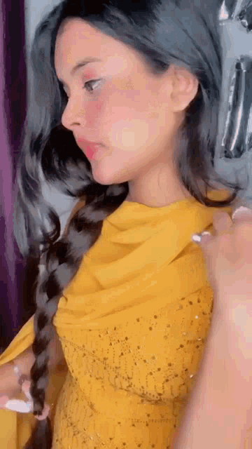 a woman wearing a yellow dress and a braided hair .