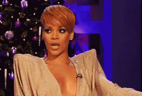 a woman in a very revealing dress is standing in front of a christmas tree and making a surprised face .
