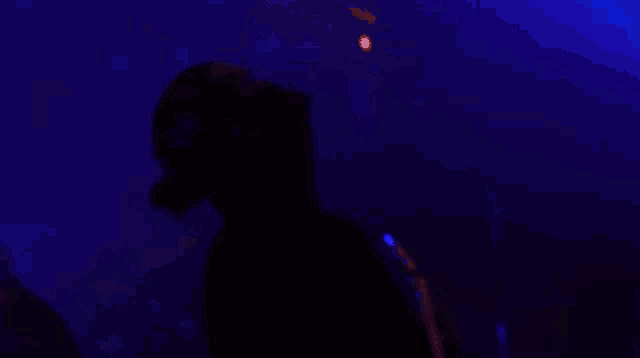a person playing a guitar in a dark room with blue lights behind them