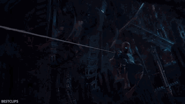 a man in a spiderman costume is hanging from a rope in the dark .