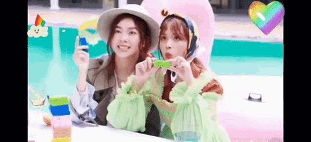 two girls are sitting next to each other in front of a swimming pool eating watermelon .