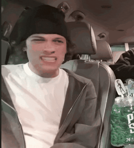 a man is sitting in a car next to a bottle of ts