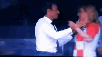 a man in a white shirt and tie is hugging another man in a red and white shirt