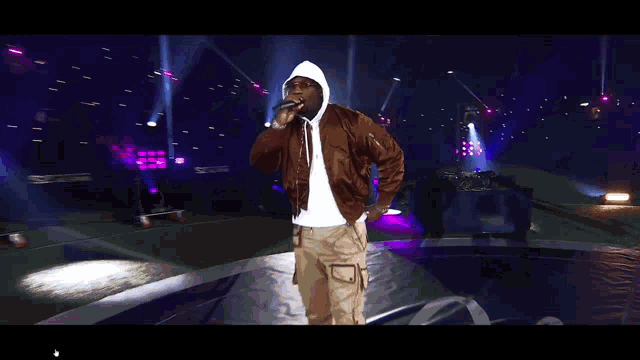 a man singing into a microphone while wearing a hoodie