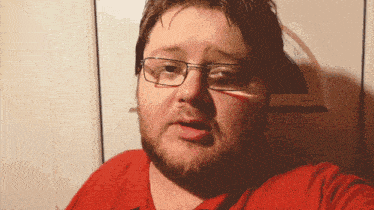 a man with glasses and a red shirt is making a funny face