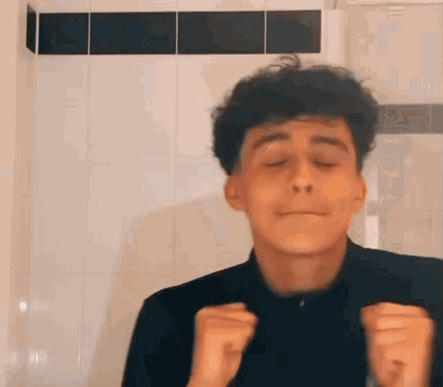 a young man with curly hair is making a funny face in front of a tiled wall