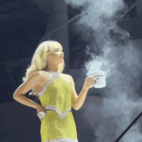 a woman in a yellow dress is holding a mug that says manchester