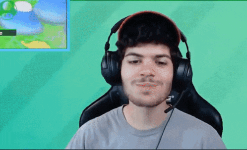 a man wearing headphones is sitting in front of a green screen .