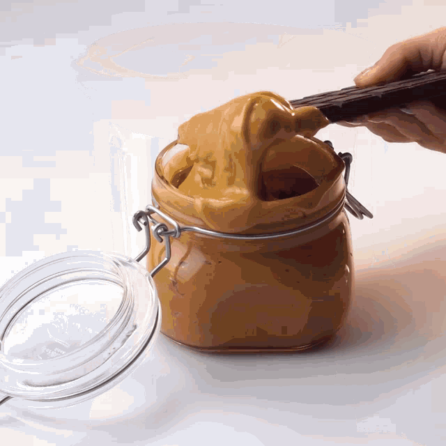 a jar of peanut butter is being scooped out with a stick