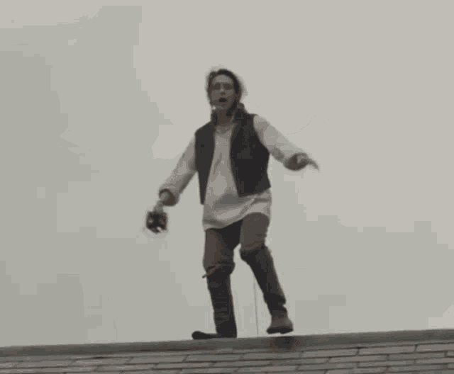 a man is holding a sword while kneeling on a roof