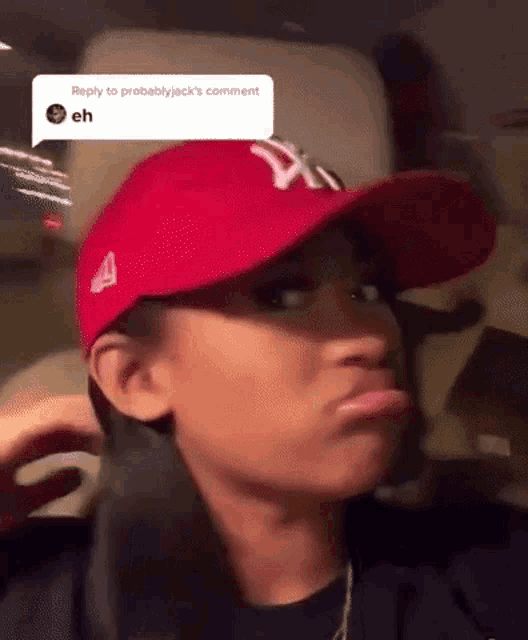 a woman wearing a red hat and a black shirt is making a funny face .