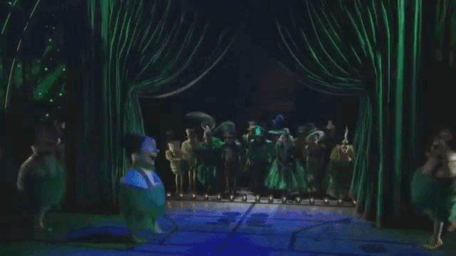 a group of people are dancing on a stage in a dark room