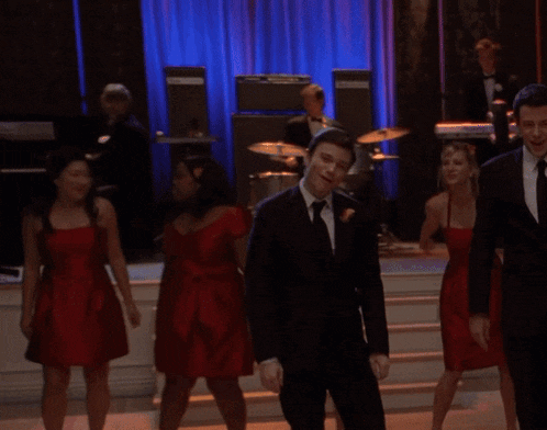 a group of people in red dresses are dancing in a room