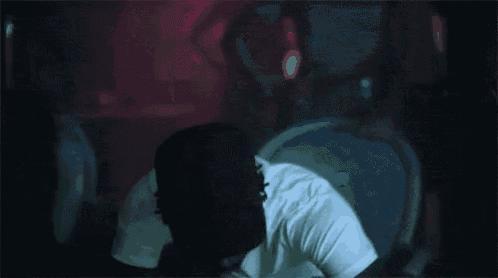 a man in a white t-shirt and hat is dancing in a club .