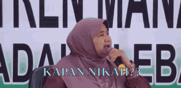 a woman in a purple hijab speaking into a microphone with the words kapan nikah written below her