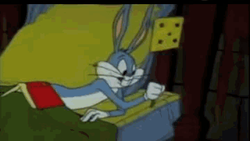 bugs bunny is laying on a bed with a piece of cheese