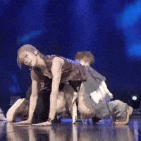 a group of people are dancing on a stage and one of them is kneeling down